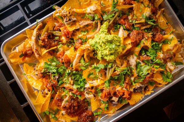 Nachos on a sheet pan topped with guacamole