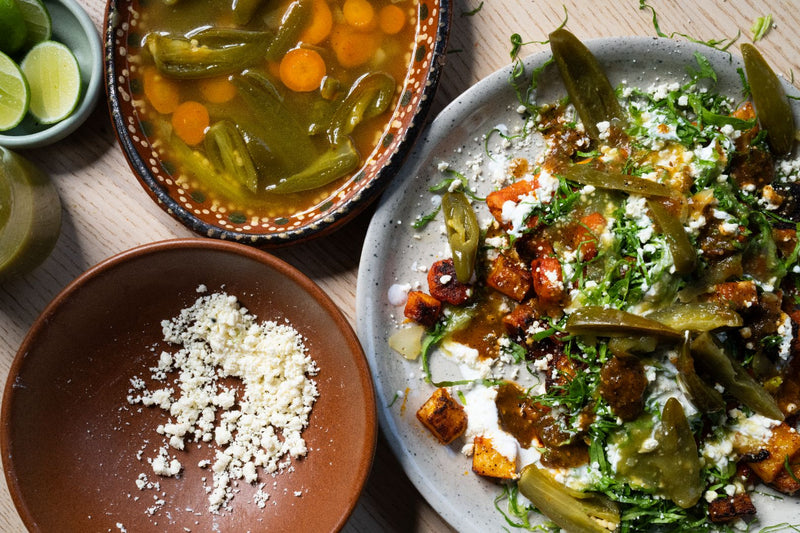 Plato de enchiladas michoacanas, cubiertas con papas, zanahorias, queso, crema, salsa, lechuga y jalapeños.