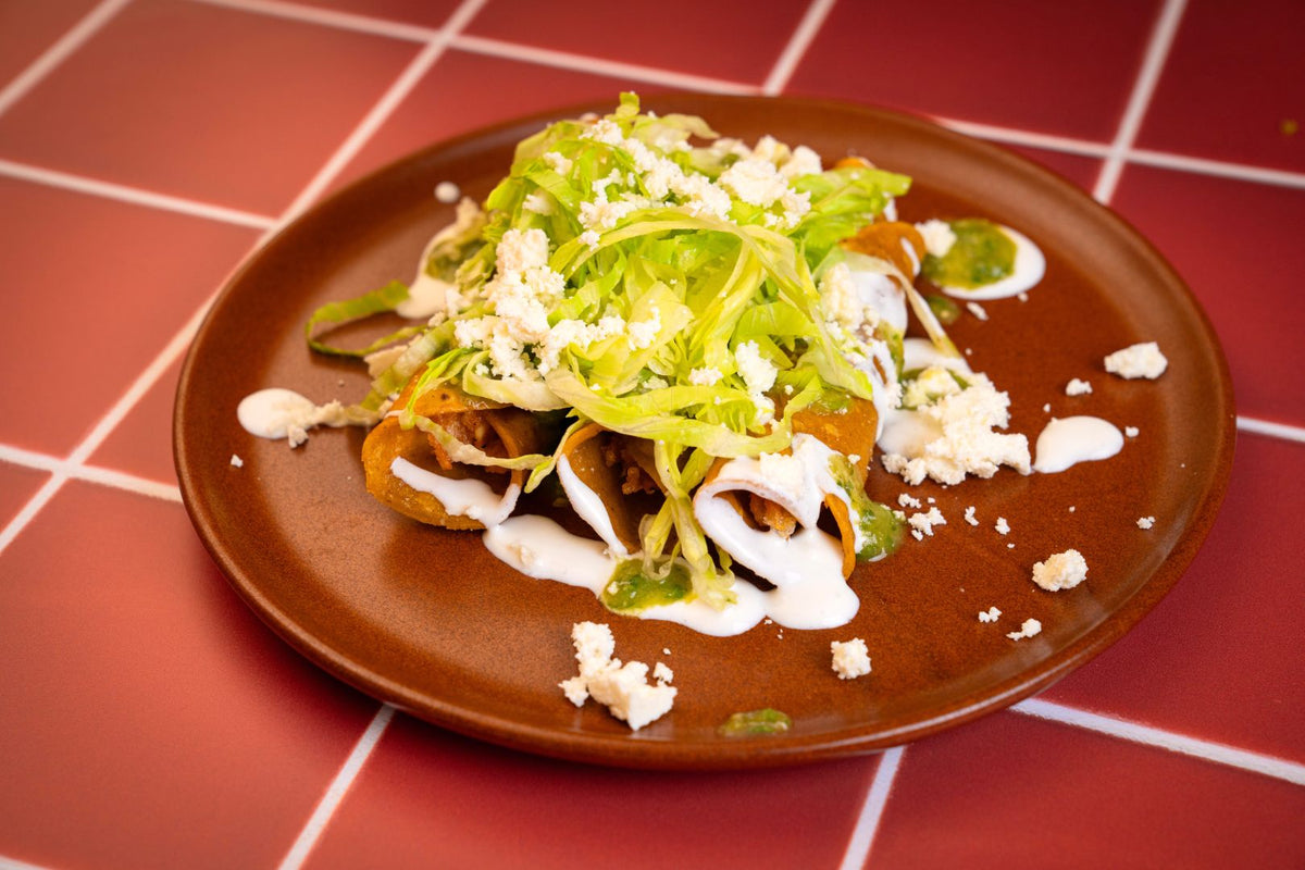 Flautas topped with lettuce, crema, and queso fresco
