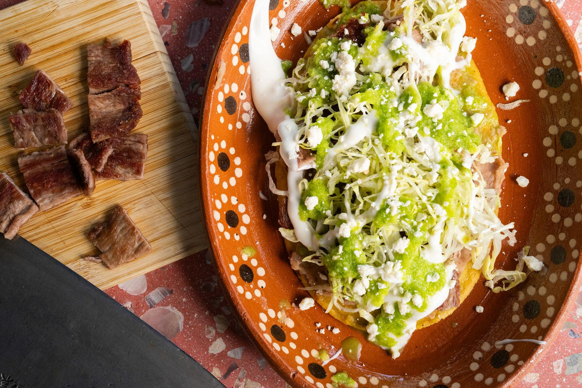 Huarache topped with carne asada, lettuce, crema, and salsa
