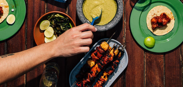 Plate of al pastor kebabs tacos with garnishes and fresh tortillas