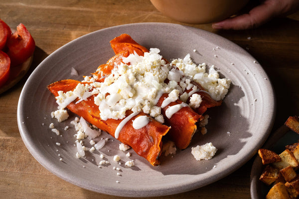 Plato de enchiladas con queso desmenuzado y crema